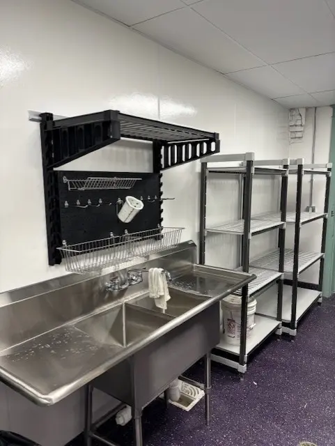 Elevation shelving installed beside a three-compartment sink