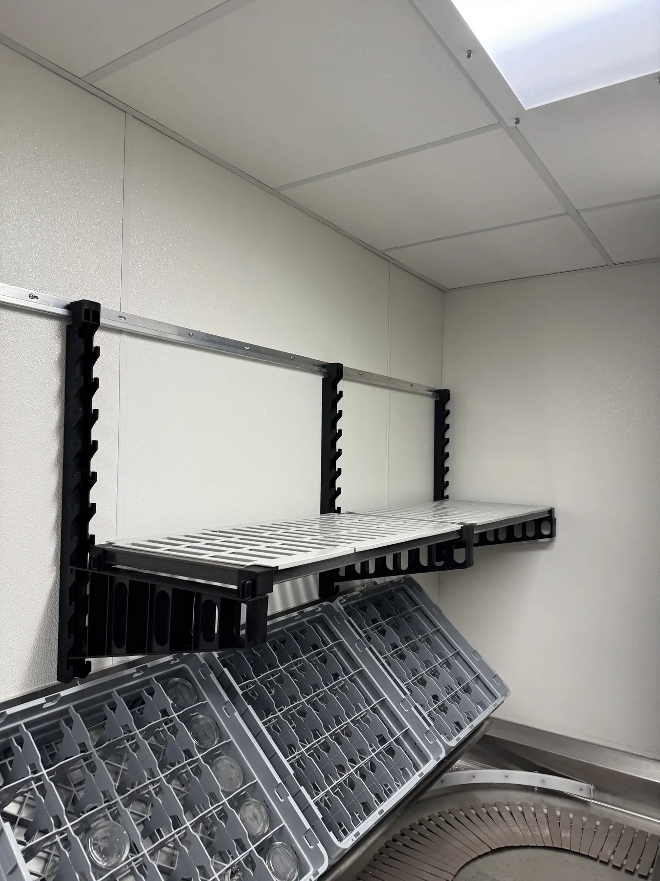 Wall-mounted shelf positioned above a commercial dish rack